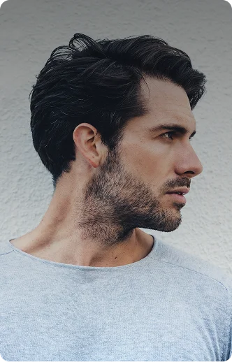 Profile of a man with dense, styled hair looking to the side outdoors - Hair Restoration in New York, NY