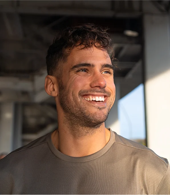 Man smiling brightly with healthy, full hair in natural sunlight - Hair Restoration in New York, NY