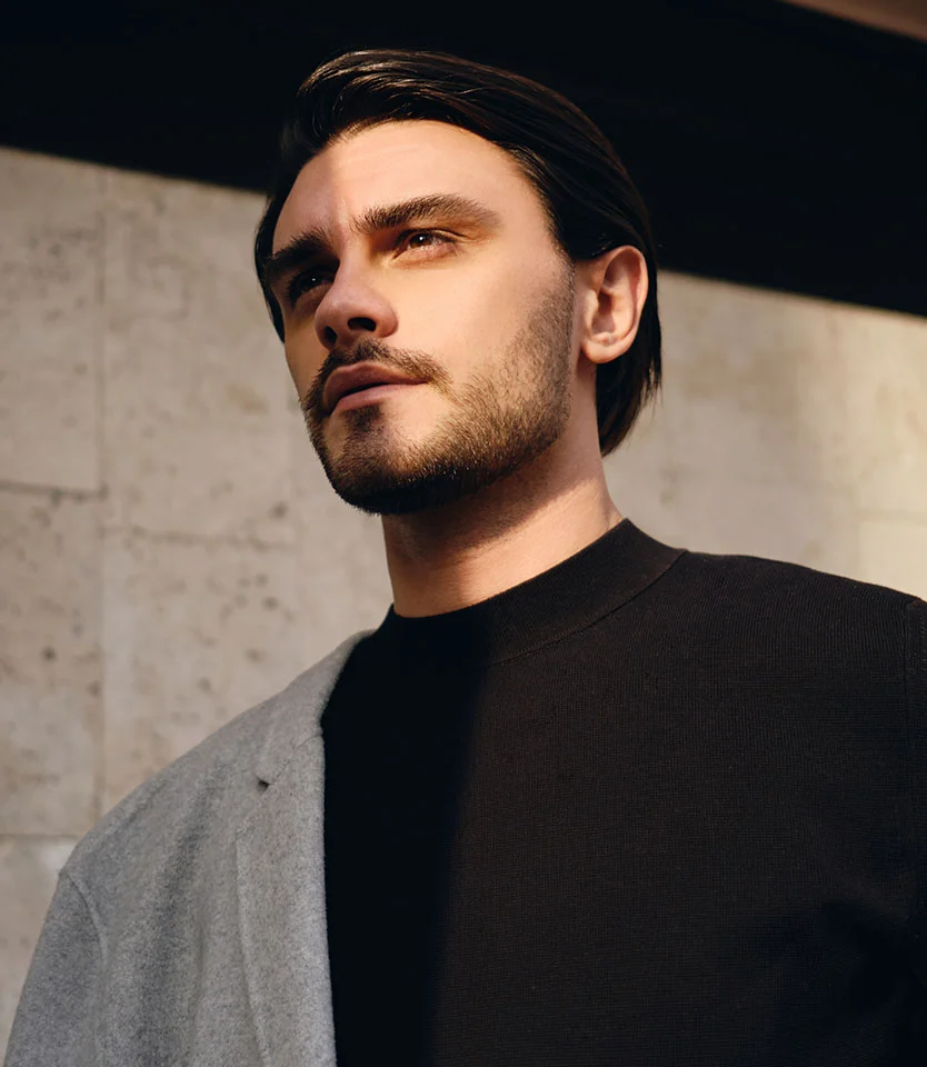 Man in a dark sweater and coat looking upward with warm sunlight across his face - Eyebrow Transplant in New York, NY