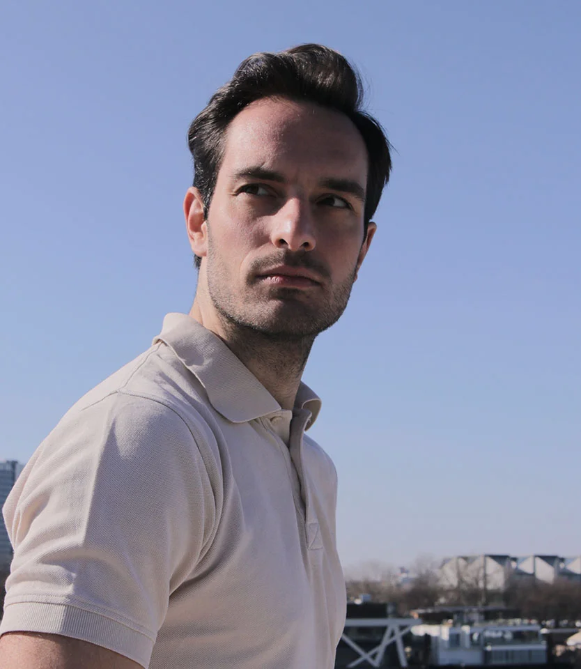 Man in a light polo shirt looking to the side outdoors under a clear blue sky - Hair Loss in Men in New York, NY