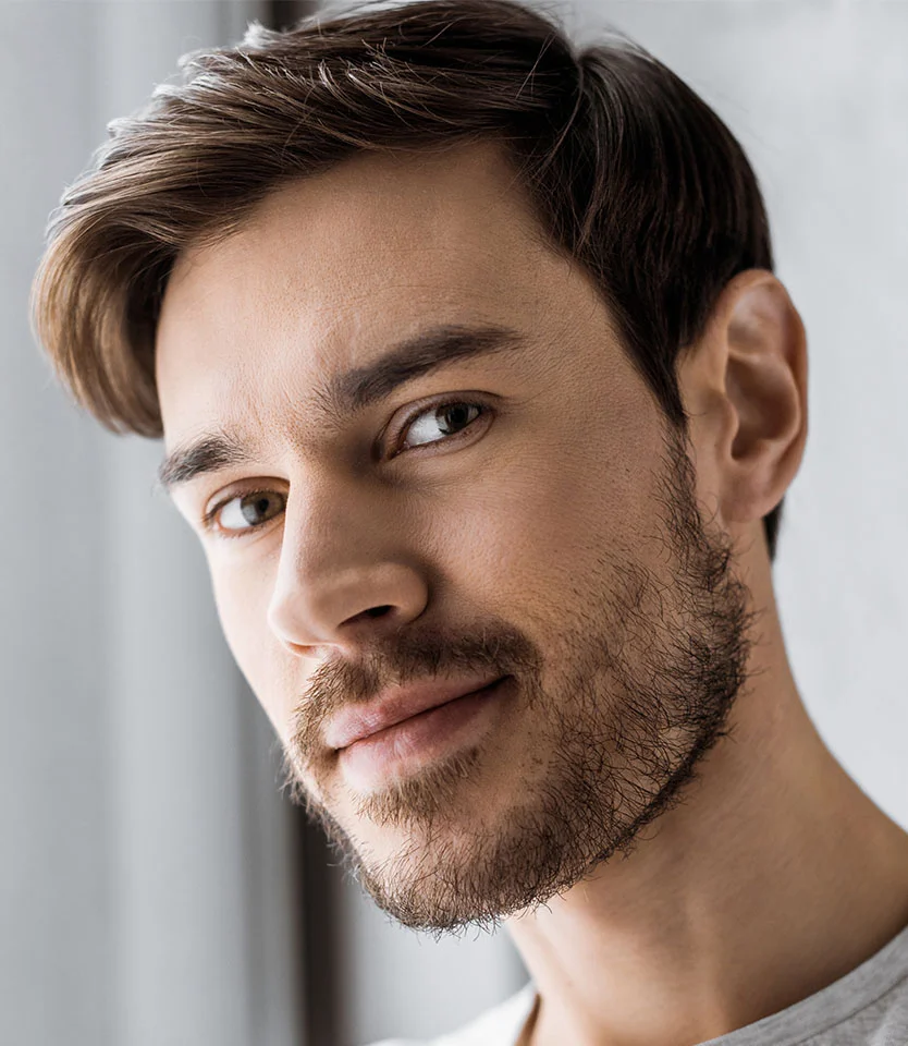 Close-up of a man with short brown hair and light stubble looking confidently toward the camera - Propecia in New York, NY